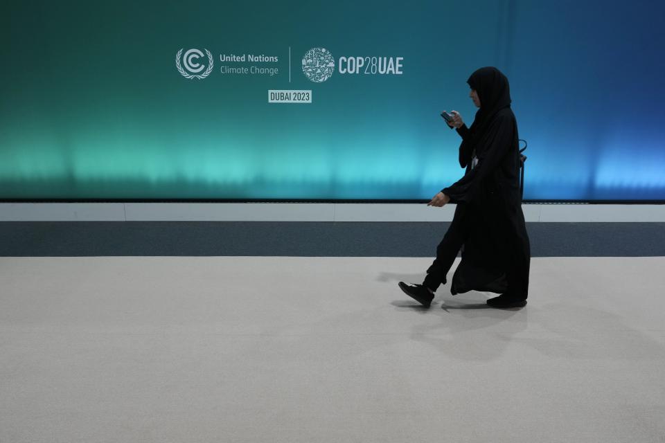 A person walks past a logo at the media center ahead of the COP28 U.N. Climate Summit, Tuesday, Nov. 28, 2023, in Dubai, United Arab Emirates. (AP Photo/Peter Dejong)