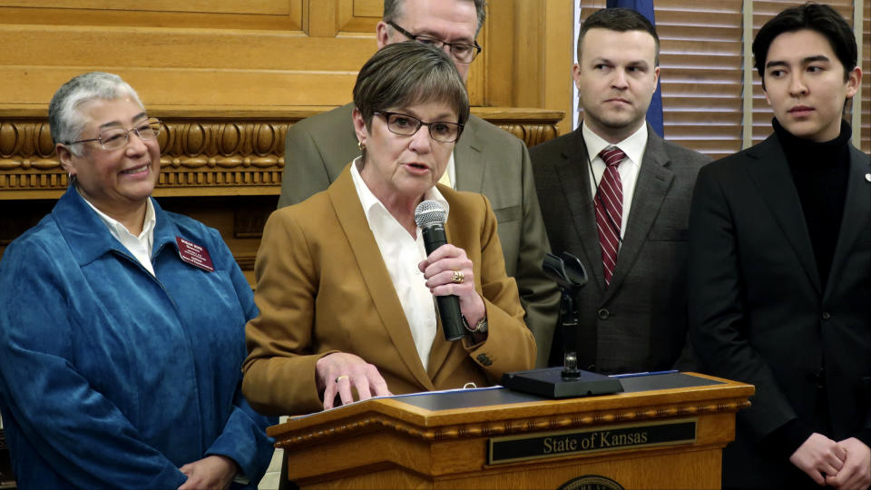 FILE- In this Jan. 15, 2019 file photo, Kansas Gov. Laura Kelly discusses a new executive order that reinstates a past ban on anti-LGBT bias in state employment decisions and extends the policy to government contractors, at the Statehouse in Topeka, Kan. Standing to the Democratic governor's left is state Rep. Susan Ruiz, D-Shawnee, one of two openly LGBT lawmakers elected last year. (AP Photo/John Hanna, File)