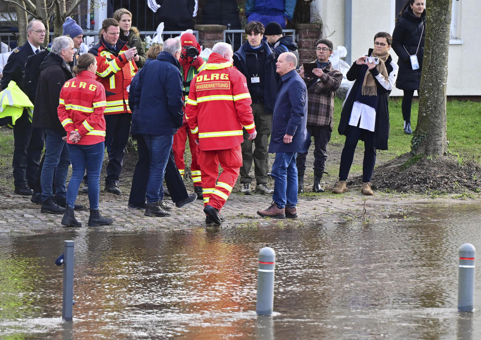 Federal Chancellor Olaf Scholz, center, talks to rescue workers from the German Life Saving Association during his visit to the flood area at the confluence of the Weser and Aller rivers, Germany, Sunday, Dec. 31, 2023. Chancellor Olaf Scholz took a sightseeing flight in an air force helicopter to gain an impression of the flood situation in the north of Lower Saxony. (Philipp Schulze/dpa via AP)