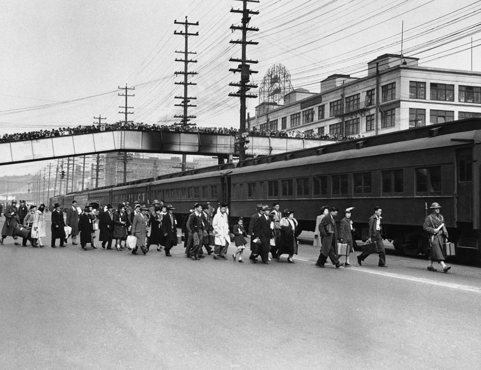 <p>Seattle crowds jam an overhead walk to witness mass evacuation of Japanese from Bainbridge Island, Washington, March 30, 1942. Somewhat bewildered, but not protesting, some 225 Japanese men, women and children were taken by ferry, bus and train to California internment camps. Evacuation was carried out by the army. (AP Photo) </p>