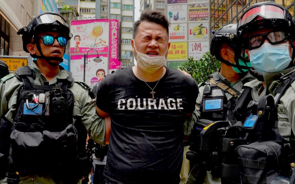 A pro-democracy lawmaker is detained by police officers after being pepper-sprayed at a protest in July 2020 - Vincent Yu /AP