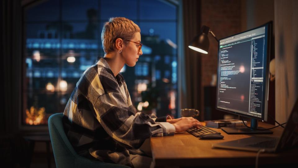 A computer programmer working at a desk in an apartment.