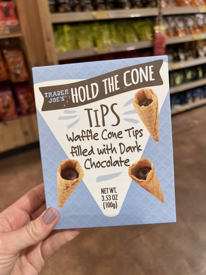 Hand holding a box of Trader Joe's Hold the Cone ice cream treats, featuring waffle cones with dark chocolate tips