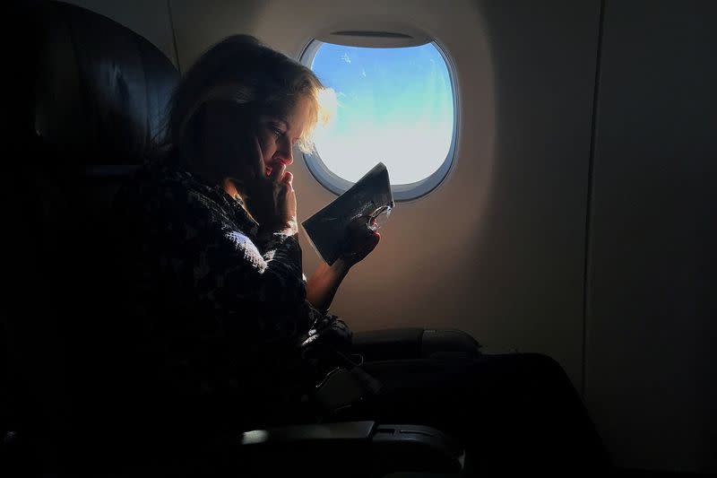 FILE PHOTO: A woman reads while sitting in a business class seat on a flight from New York City to Washington D.C.