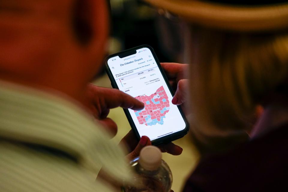 Aug 8, 2023; Columbus, Ohio, USA;  Dierdre Wedig of the North Side and Mike Duco of the Northwest Side check the statewide results of Issue 1 during an election night party at the Columbus Fire Fighters Local 67. 