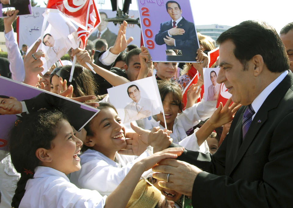 FILE - In this Nov.7, 2008 file photo, children welcome Tunisian President Zine El Abidine Ben Ali as he arrives to a meeting marking the 21st anniversary of his accent to powe in Tunis. Tunisia's autocratic ruler Zine El Abidine Ben Ali, toppled in 2011, died in exile in Saudi Arabia. (AP Photo/Hassene Dridi, File)