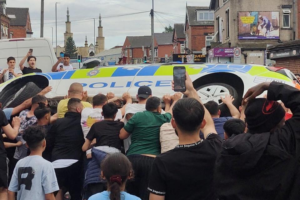 Protesters overturn a police vehicle during unrest in Harehills (Reuters)