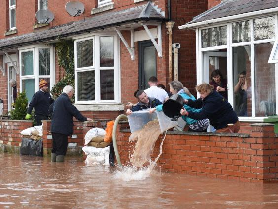 Families bail water out of flooded homes after the River Wye burst its banks in Herefordshire on Monday (AFP)