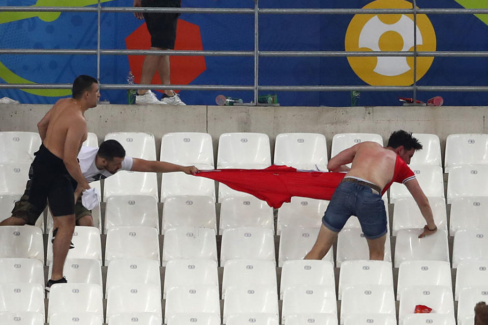 Three individuals stretching a large red banner across stadium seats