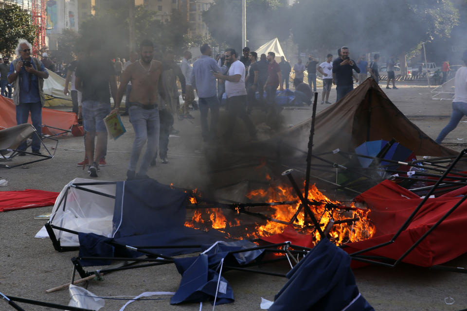 FILE - In this Oct. 29, 2019 file photo, supporters of the Shiite Hezbollah group burn tents in the camp set up by anti-government protesters near the government palace, in Beirut, Lebanon. Lebanon’s protests have shown unusual overt anger at the country’s powerhouse, Hezbollah. (AP Photo/Bilal Hussein, File)