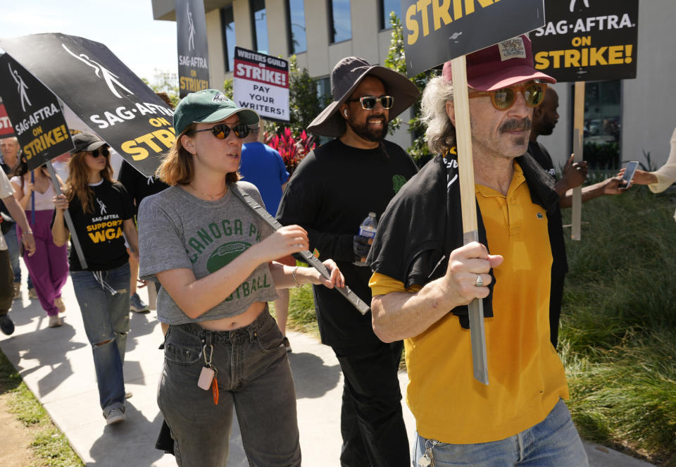 Marc Maron, right, Hannah Einbinder, from second left, and Debby Ryan walk on a picket line outside Netflix studios on Friday, July 21, 2023, in Los Angeles. The actors strike comes more than two months after screenwriters began striking in their bid to get better pay and working conditions. (AP Photo/Chris Pizzello)