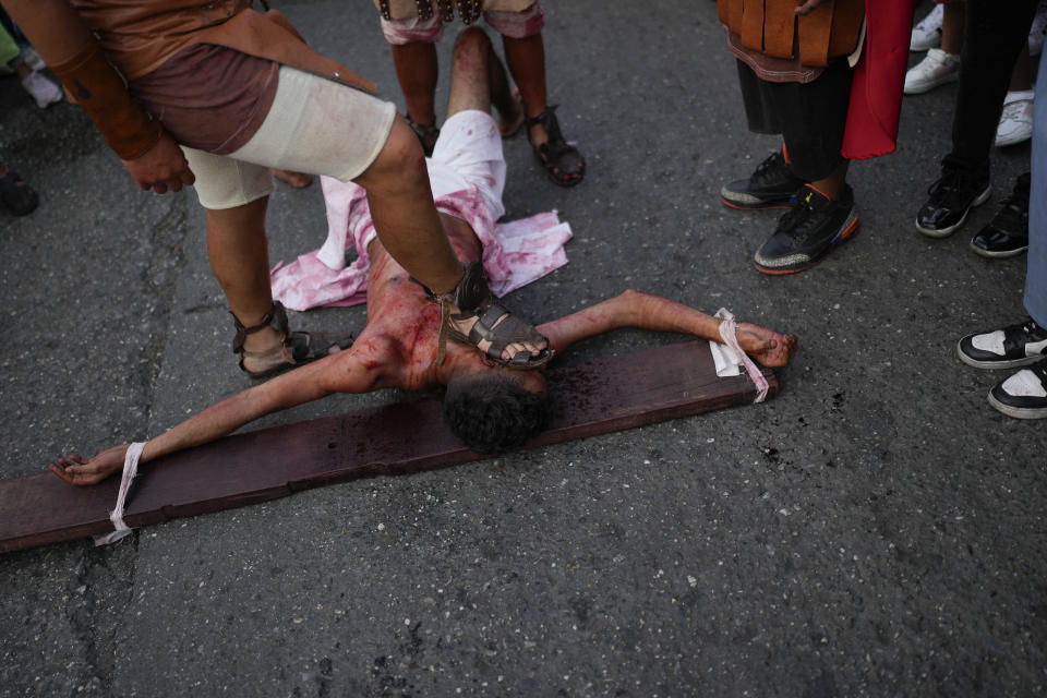 A devotee dressed as a Roman soldier places his foot on the face of penitent playing the role of one of two thieves sentenced to be crucified alongside Jesus Christ, during a Way of the Cross reenactment, as part of Holy Week celebrations in the Petare neighborhood of Caracas, Venezuela, Friday, March 29, 2024. Holy Week commemorates the last week of the earthly life of Jesus Christ culminating in his crucifixion on Good Friday and his resurrection on Easter Sunday. (AP Photo/Matias Delacroix)