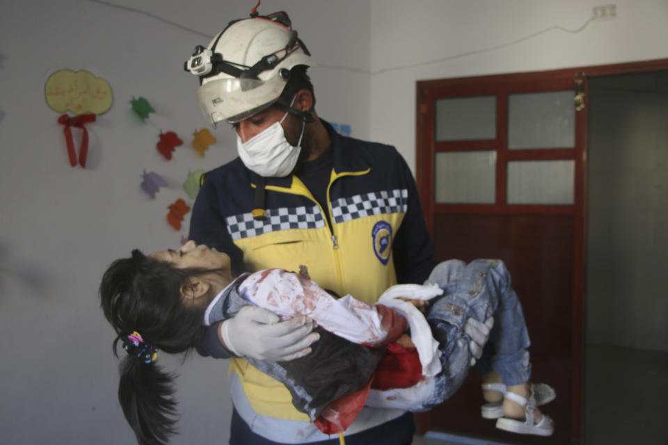 This photo provided by the Syrian Civil Defense White Helmets, which has been authenticated based on its contents and other AP reporting, shows Syrian White Helmet civil defense workers carrying a casualty, in the northern town of Ariha, in Idlib province, Syria, Wednesday, Oct. 20, 2021. Rescue workers reported several people were killed, including children and a woman, in shelling by Syrian government forces on Ariha, in the last rebel enclave in the country's northwest. (Syrian Civil Defense White Helmets via AP)