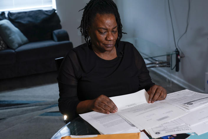 Debra Long looks through documents about the murder of her son, Randy Long, and photographs from his life, at her home in Poughkeepsie, N.Y., April 19, 2023. An AP examination of data from 23 states shows that Black people are disproportionately denied aid from programs that reimburse victims of violent crime. (AP Photo/Seth Wenig)