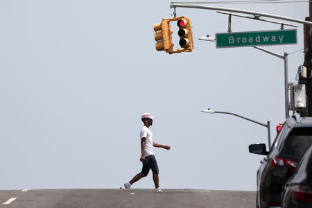 A man crosses West 145th Street during very hot weather in the Washington Heights section of Manhattan in New York City, New York, U.S., June 18, 2018. REUTERS/Mike Segar