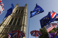 European flags placed by remain in the European Union anti-Brexit supporters fly backdropped by the Houses of Parliament in London, Tuesday, Oct. 22, 2019. British Prime Minister Boris Johnson's European Union divorce bill faces two votes Tuesday, with lawmakers first being asked to approve it in principle, followed by a vote on the government's schedule for debate and possible amendments. (AP Photo/Matt Dunham)