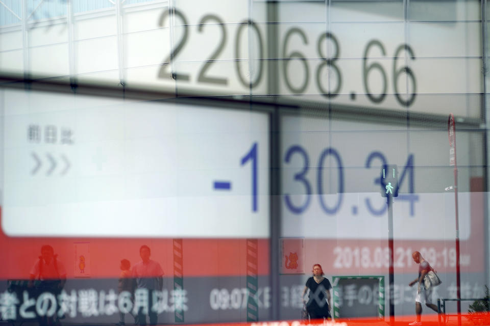 Pedestrians are reelected on an electronic stock board showing Japan's Nikkei 225 index at a securities firm Tuesday, Aug. 21, 2018, in Tokyo. Asian shares are mixed amid doubts on the prospects for resolving the trade dispute between the U.S. and China. (AP Photo/Eugene Hoshiko)