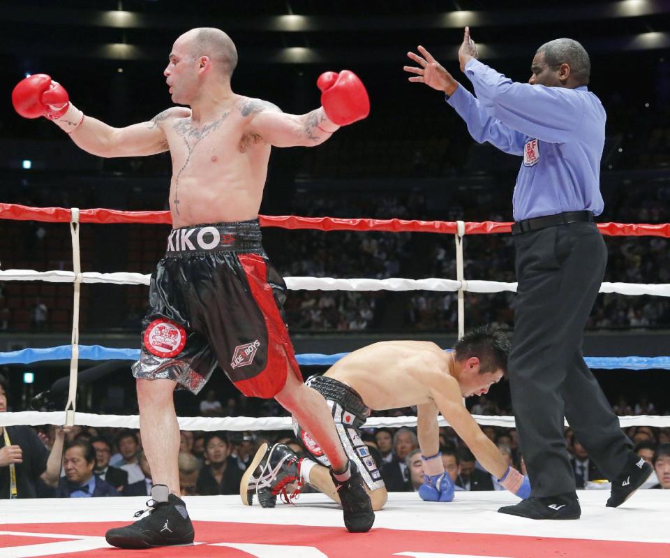 Spanish champion Kiko Martinez celebrates as Japanese challenger Hozumi Hasegawa kneels down on the mat in the seventh round of their IBF super bantamweight boxing title bout in Osaka, western Japan, Wednesday, April 23, 2014. Martinez defended his title by technical knockout in the seventh round. (AP Photo/Kyodo News) JAPAN OUT, CREDIT MANDATORY