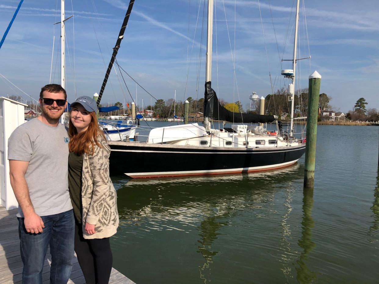 Casey and her partner posing outside in front of their sailboat
