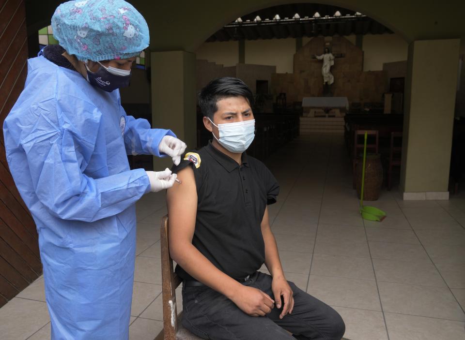 A nurse gives a shot of the Sinopharm COVID-19 vaccine to Cesar Tapia at the door of a church during a house to house vaccination campaign in the Villa Maria del Triunfo neighborhood of Lima, Peru, Wednesday, Oct. 13, 2021. (AP Photo/Martin Mejia)