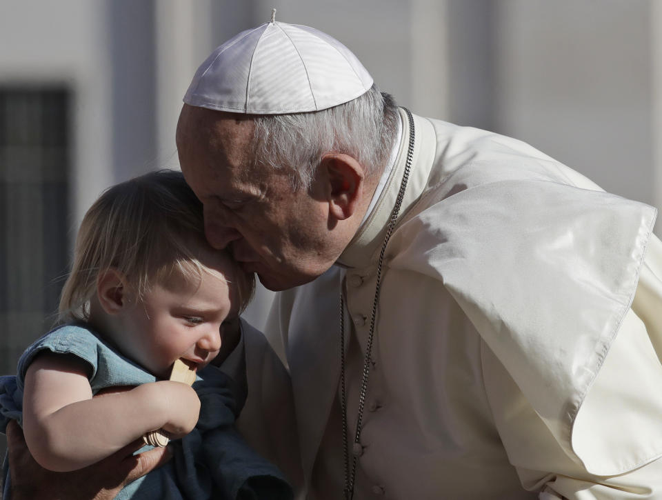 El papa Francisco besa a un niño al arribar a la plaza de San Pedro en el Vaticano para su audiencia general semanal, 5 de septiembre de 2018. (AP Foto/Alessandra Tarantino)