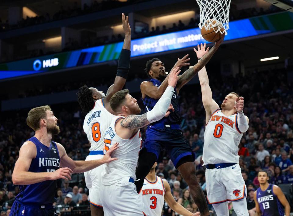 Sacramento Kings guard Malik Monk is fouled as he drives between New York Knicks guard OG Anunoby (8), center Isaiah Hartenstein (55) and guard Donte DiVincenzo (0) during a game Saturday at Golden 1 Center.