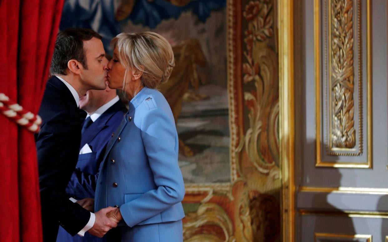 French President Emmanuel Macron kisses his wife Brigitte Trogneux during the handover ceremony in Paris - REUTERS