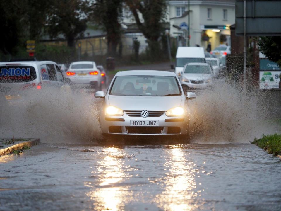 Drivers struggle through a flooded road in Barnham, West Sussex (PA)