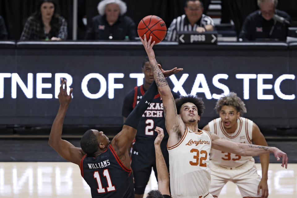 Texas' Christian Bishop (32) tips the ball off over Texas Tech's Bryson Williams (11) during the first half of an NCAA college basketball game on Tuesday, Feb. 1, 2022, in Lubbock, Texas. (AP Photo/Brad Tollefson)