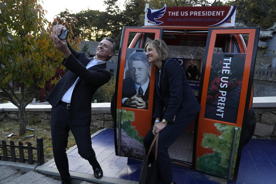 FILE - California Gov. Gavin Newsom, left, takes a selfie with a commemorative cable car carriage featuring former U.S. President Bill Clinton during a visit to the Mutianyu Great Wall on the outskirts of Beijing, on Oct. 26, 2023. Gavin Newsom's trip to China, with the stated goal of working together to fight climate change, resulted in a surprise meeting with leader Xi Jinping and was filled with warm words and friendliness not seen in years in the China- U.S. relationship. (AP Photo/Ng Han Guan, File)