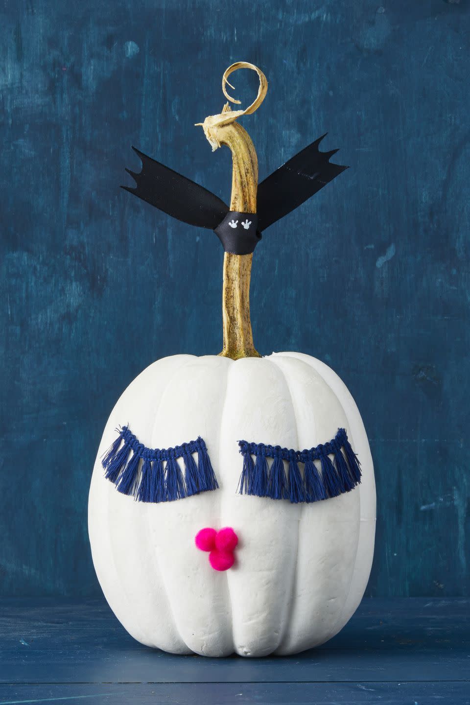 <p>Lush lashes have never been hotter — even our pumpkins are getting in on the fringe benefits! Hot-glue tassels for eyes and pom-poms for a pucker. For the bat, use a sturdy 1-inch ribbon so the wings stand up on their own. </p>