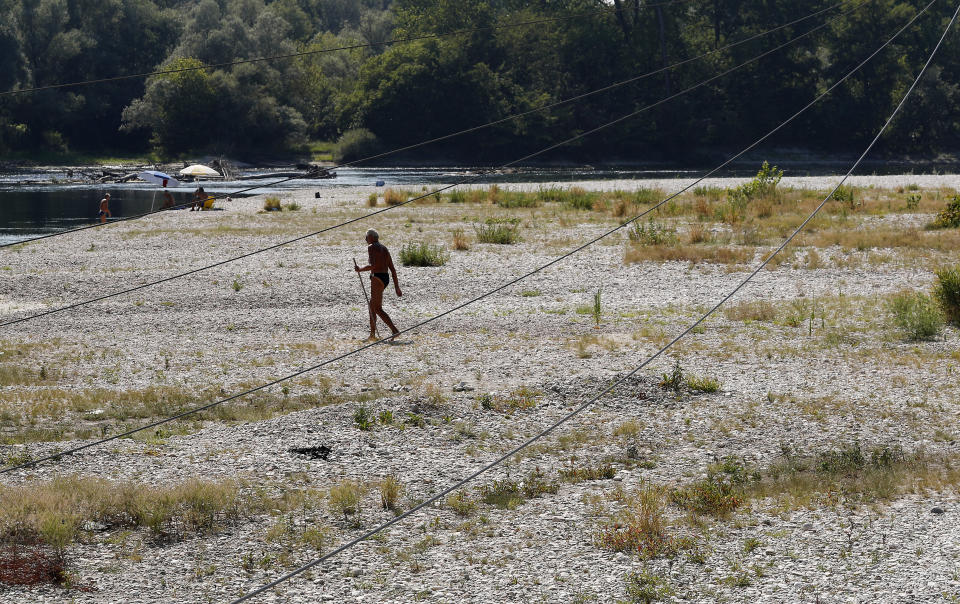 A man walks next to Ticino river in Bereguardo, near Pavia, Italy, Friday, Aug. 3, 2018. Hot air from Africa is bringing a heat wave to Europe, prompting health warnings about Sahara Desert dust and exceptionally high temperatures that could peak at 47 degrees Celsius (117 Fahrenheit). (AP Photo/Antonio Calanni)