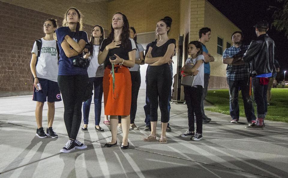 In this Thursday, Sept. 13, 2018, photo, residents watch a wildfire burning from outside Salem Hills High School in Salem, Utah. in Salem, Utah. (Qiling Wang/The Deseret News via AP)