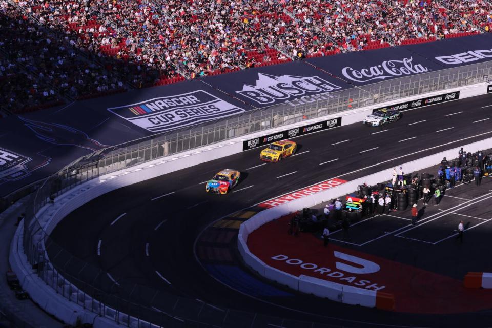 Los fanáticos de NASCAR observan y aplauden mientras los corredores recorren la pista de un cuarto de milla durante el Busch Light Clash en el Coliseo.