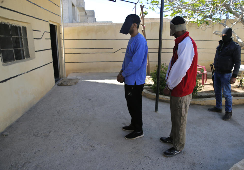 A Kurdish security officer, right, escorts Alexanda Amon Kotey, left, and El Shafee Elsheikh, center, allegedly among four British jihadis who made up a brutal Islamic State cell dubbed "The Beatles," at a security center in Kobani, Syria, Friday, March 30, 2018. “The Beatles” terror cell is believed to have captured, tortured and killed hostages including American, British and Japanese journalists and aid workers. (AP Photo/Hussein Malla)