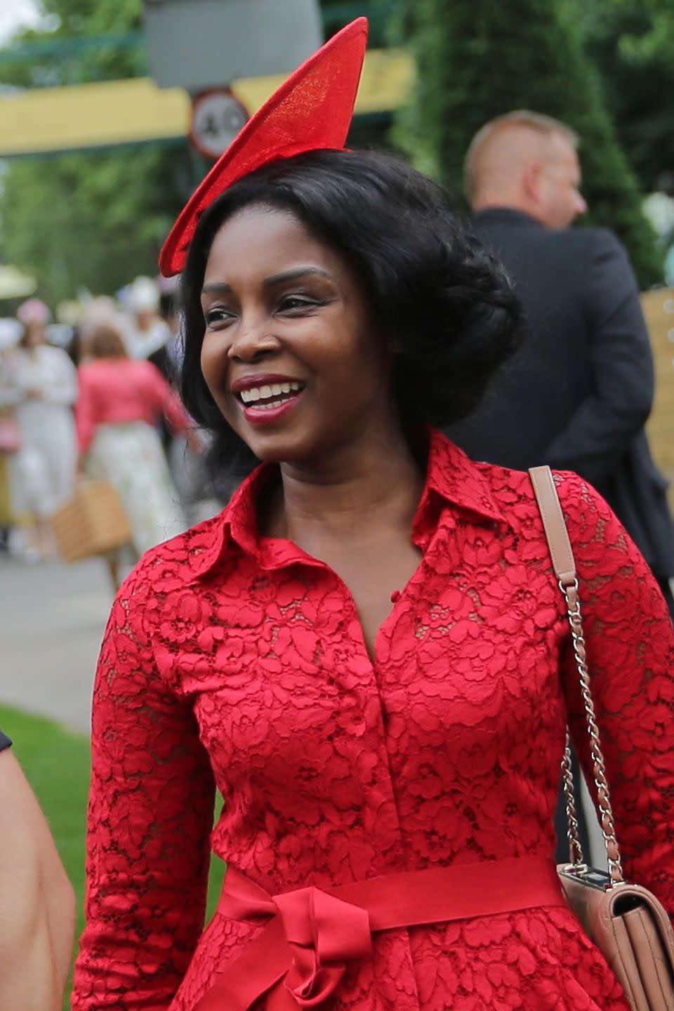 <p>A smiling guest paired her red lace dress with a pointed headpiece. </p>