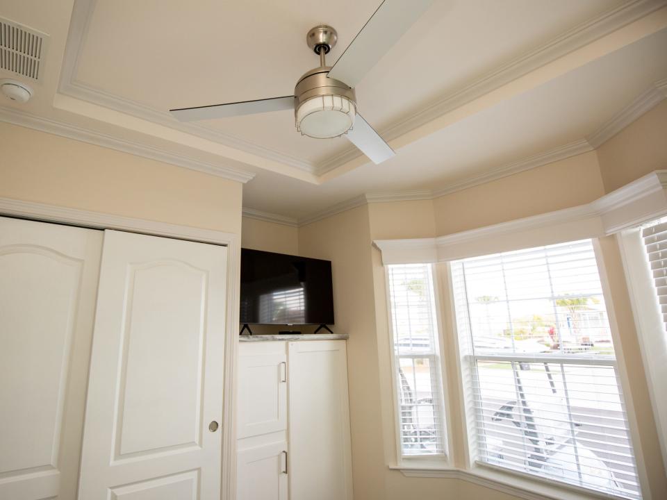 A closet, ceiling fan, TV, and windows.