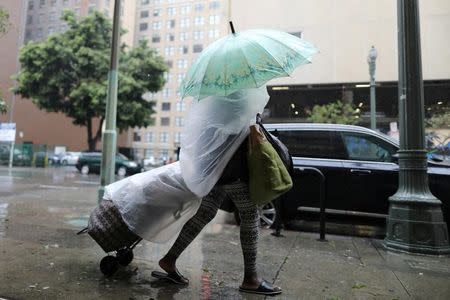 A woman walks through heavy rain in Los Angeles, February 17, 2017. REUTERS/Lucy Nicholson