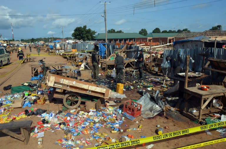 Nigerian security officers stand next to rubble in Kuje, near Abuja, on October 3, 2015, after two bomb blasts ripped through the outskirts of Nigeria's capital Abuja