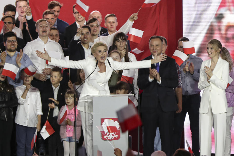Incumbent President Andrzej Duda, center, applauds as his wife Agata Kornhauser-Duda, gestures while speaking to supporters, in Pultusk, Poland, Sunday, July 12, 2020. An exit poll in Poland's presidential runoff election shows a tight race that is too close to call between the conservative incumbent, Andrzej Duda, and the liberal Warsaw mayor, Rafal Trzaskowski.(AP Photo/Czarek Sokolowski)