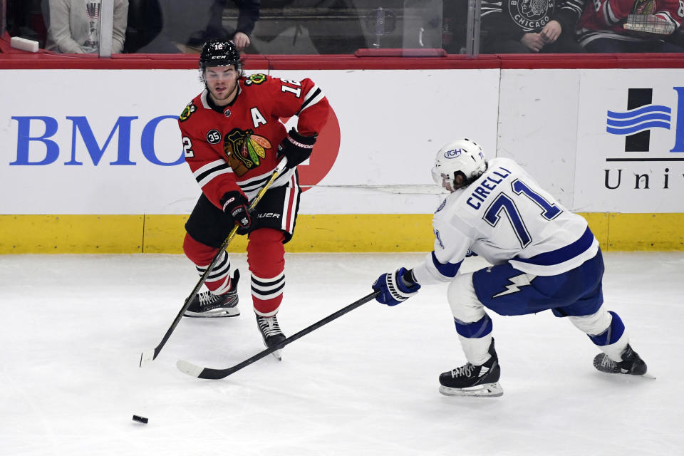 Chicago Blackhawks left wing Alex DeBrincat (12) and Tampa Bay Lightning center Anthony Cirelli (71) fight for the puck during the second period of an NHL hockey game, Sunday, March 6, 2022, in Chicago. (AP Photo/Matt Marton)