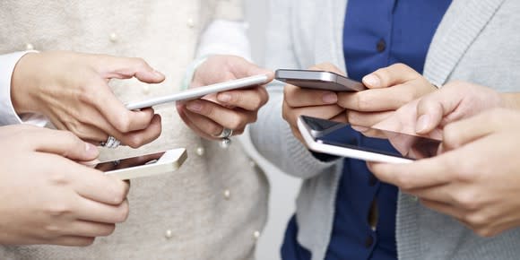 Four adults using their smartphones.