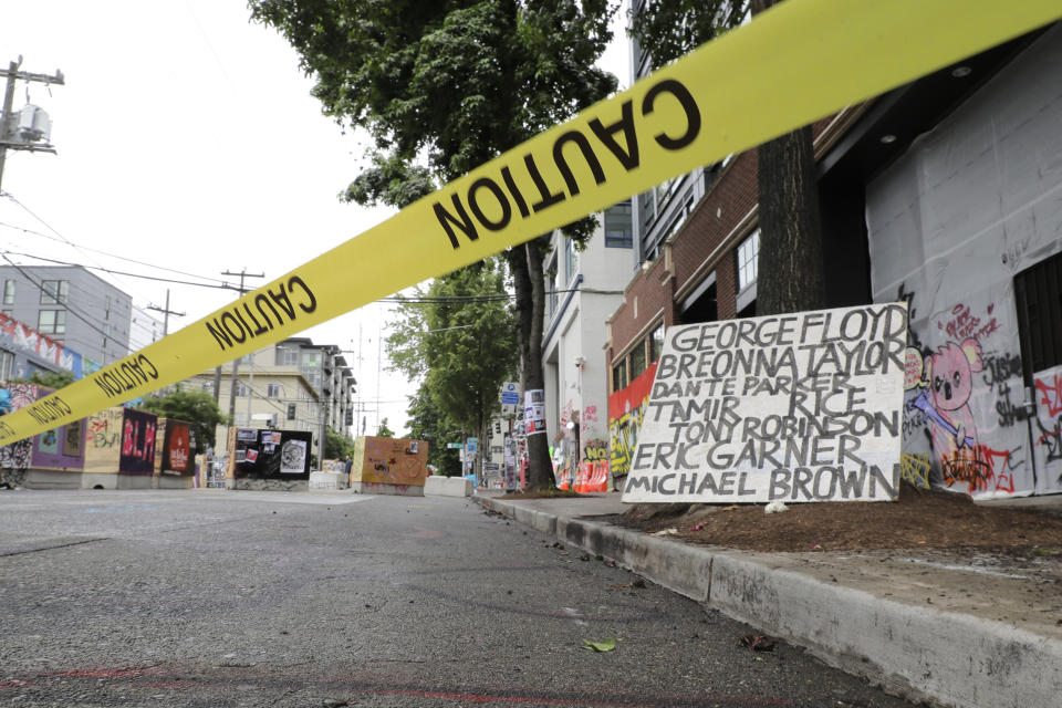 Caution tape is shown near a sign with the names of victims of police violence, Saturday, June 20, 2020, at the Capitol Hill Occupied Protest zone in Seattle. It is unknown who put the tape in place. A pre-dawn shooting near the area left one person dead and critically injured another person, authorities said Saturday. The area has been occupied by protesters after Seattle Police pulled back from several blocks of the city's Capitol Hill neighborhood near the Police Department's East Precinct building. (AP Photo/Ted S. Warren)