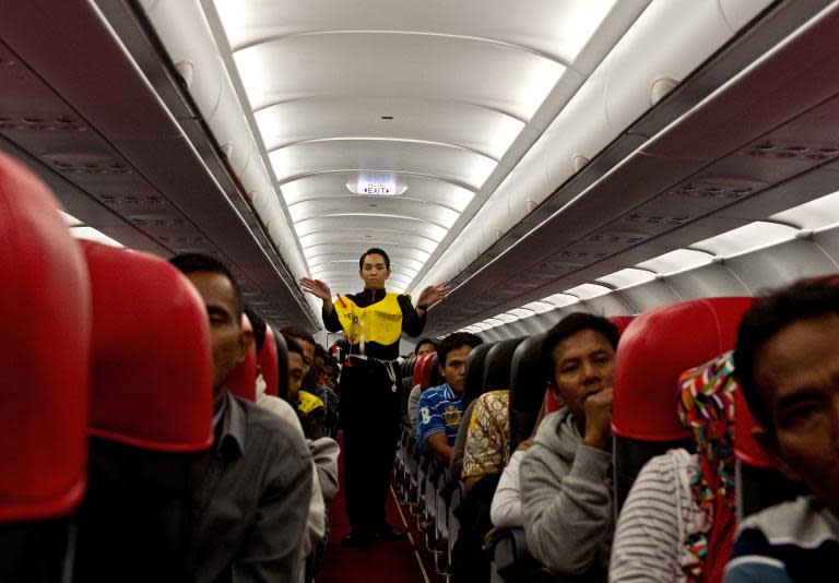 An AirAsia flight attendant (C) gives a safety demonstration on a flight preparing to depart from Kuala Lumpur to Surabaya at Kuala Lumpur International Airport 2 in Sepang