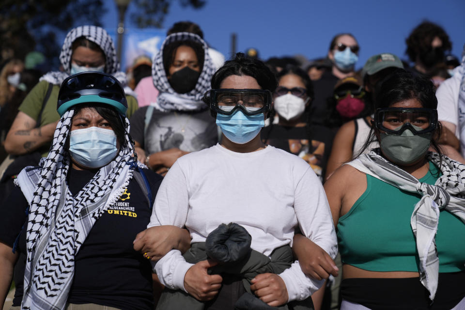 Pro-Palestinian demonstrators wearing hatta scarves and goggles lock arms forming a human chain on the UCLA campus, in Los Angeles, May 1, 2024. (AP Photo/Jae C. Hong)