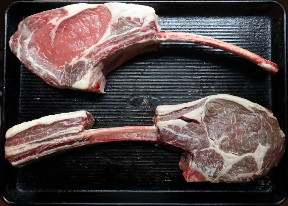 Two large raw tomahawk steaks on a grill pan