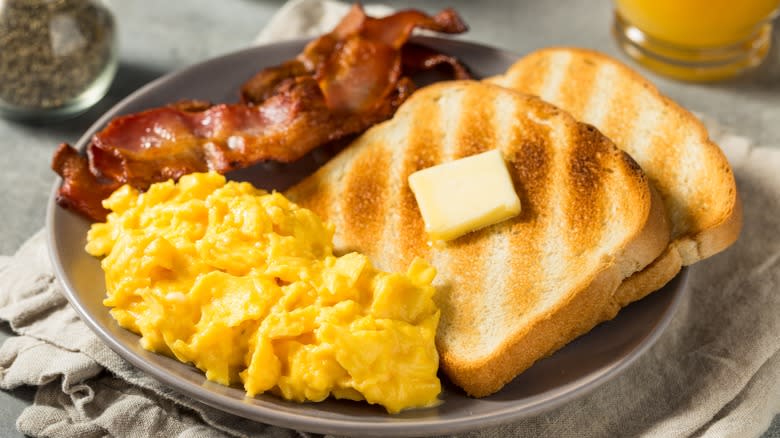 plate of scrambles eggs, bacon, toast