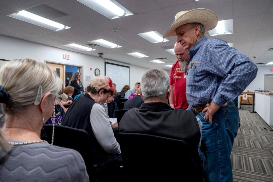 Curt Miller, right, pastor of the East Mountain Cowboy Church in Edgewood, prays with people attending the Town Council meeting, in Edgewood, N.M., Tuesday, April 25, 2023. Residents flocked to a public meeting Tuesday to discuss whether the town should adopt a local abortion-ban ordinance, extending a wave of local abortion restrictions in eastern New Mexico.