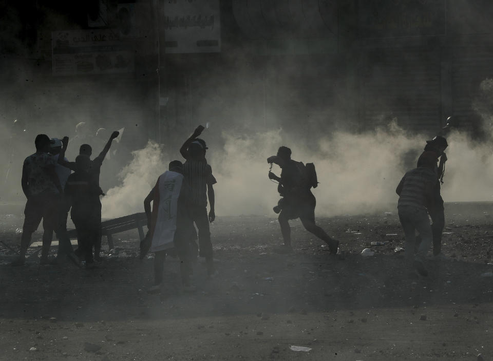 Anti-government protesters are engulfed in tear gas fired by Iraqi security forces during clashes between Iraqi security forces and anti-government protesters, in Baghdad, Iraq, Monday, Nov. 11, 2019. (AP Photo/Hadi Mizban)