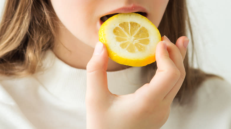 Person biting into lemon slice